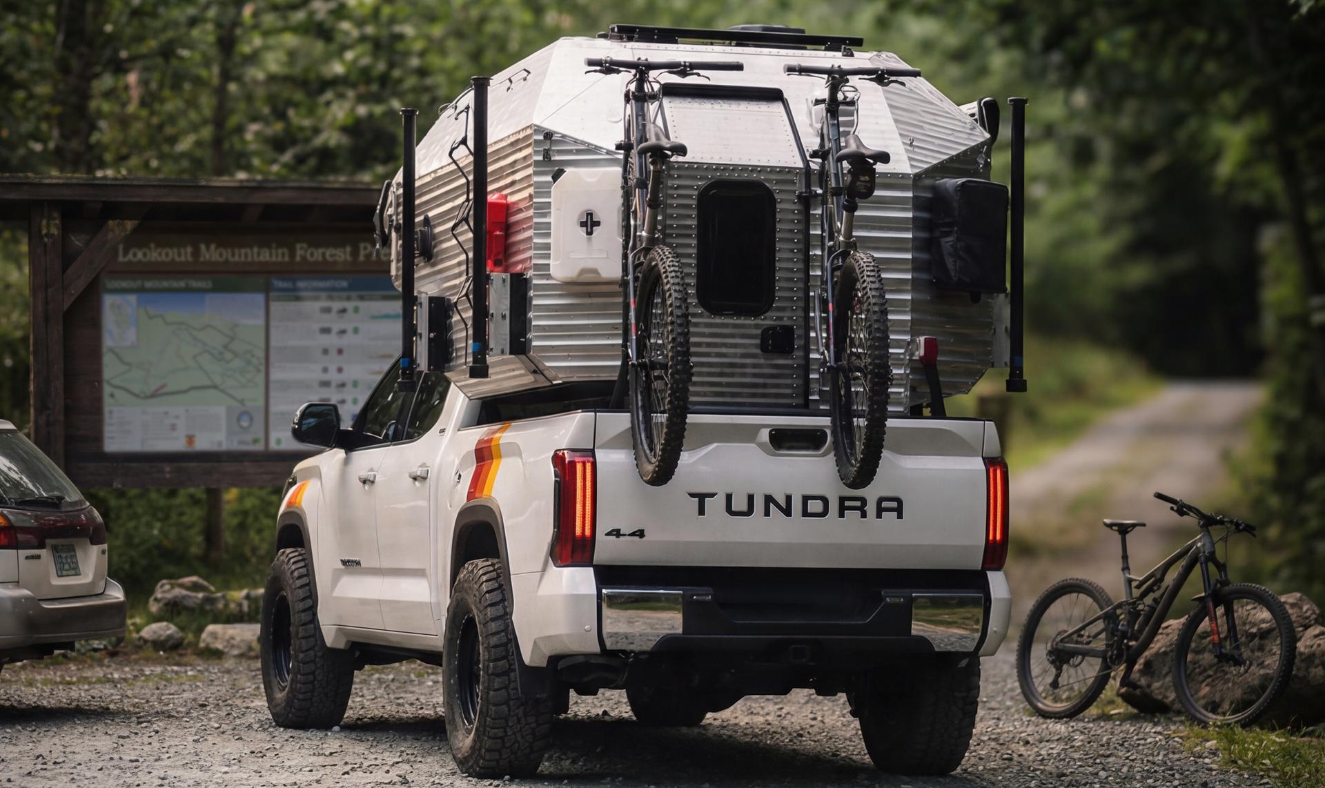 White Toyota Tundra with a Kimbo 6 Galbraith Edition truck camper, two mountain bikes on the rear rack, parked at Lookout Mountain Forest Preserve trailhead.