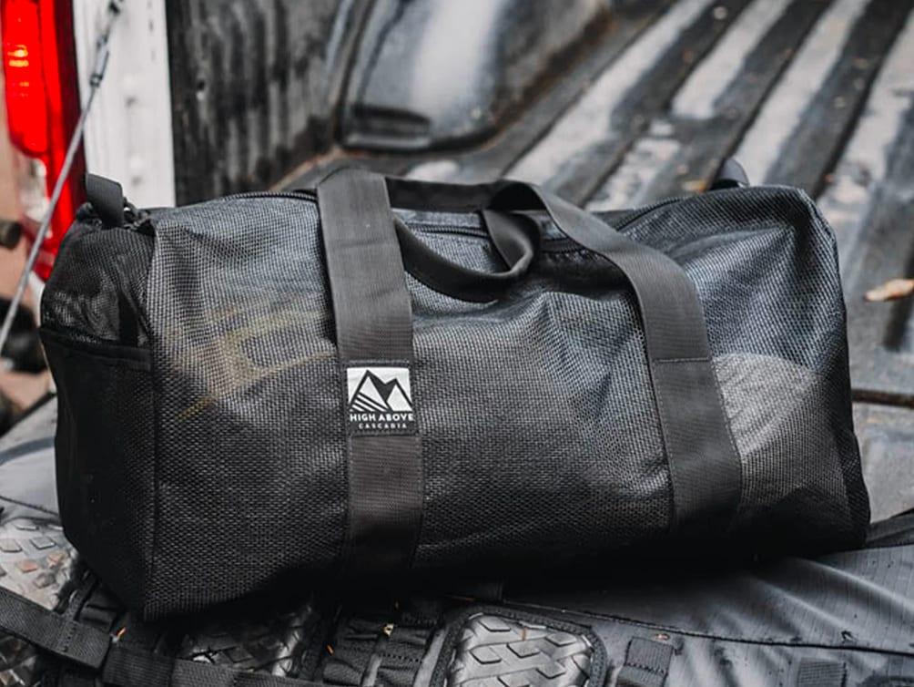 A High Above 30L Lost Lake Duffel bag in black mesh fabric, sitting in the aluminum-diamond-plate bed of a Kimbo truck camper.
